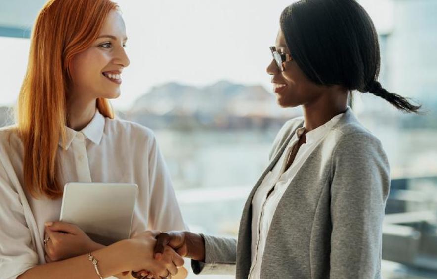 two women shaking hands in an office setting