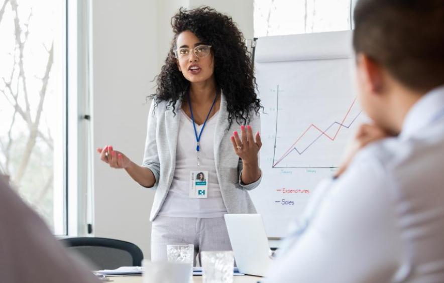 woman standing by notepad on easel presenting in a meeting