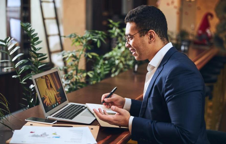 sideview of masculine dressed individual with suit jacket and glasses sitting at laptop